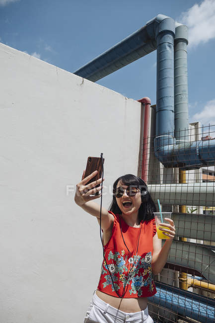 Femme asiatique avec écouteurs prenant selfie — Photo de stock