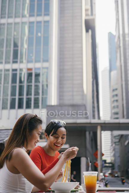 Молоді азіатські друзі їдять локшину на продовольчому корті — стокове фото