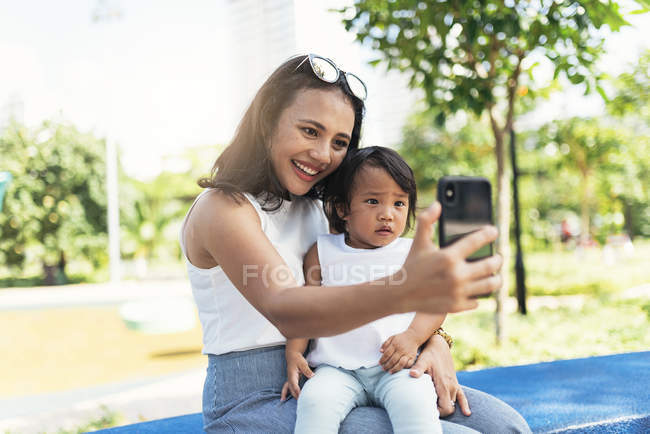 Молодая мать с азиатской дочерью делает селфи — стоковое фото