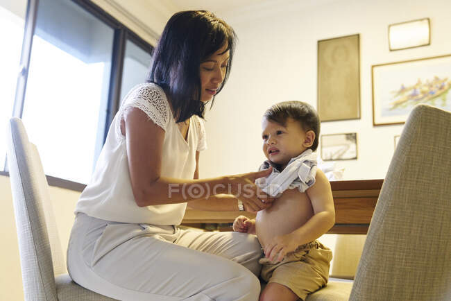 Mãe vestindo roupas para seu filho — Fotografia de Stock