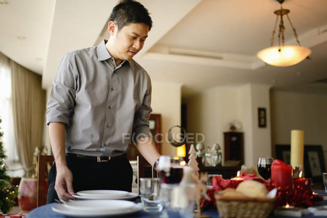 Heureux jeune asiatique homme servir noël table — Photo de stock