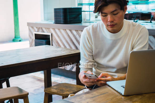 Asiático homem usando dispositivos digitais no café — Fotografia de Stock