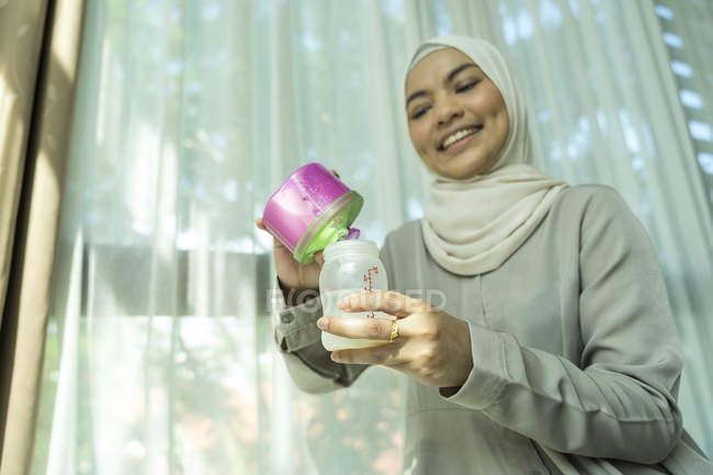 Asiatische muslimische Mutter bereitet Milch für Baby zu. — Stockfoto