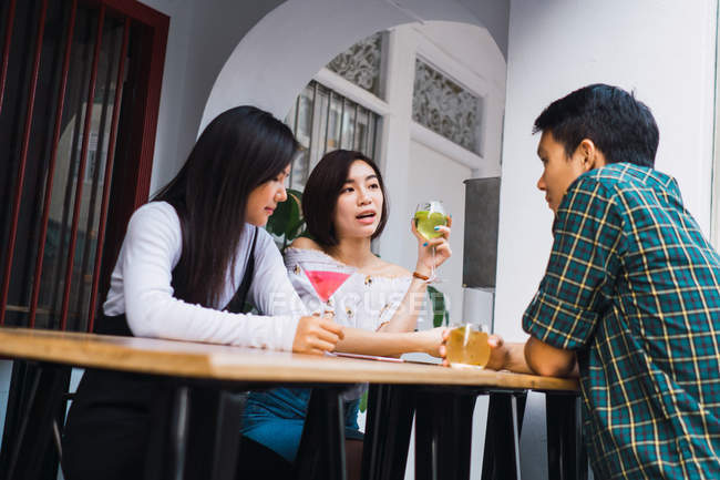 Young asian friends having drink in comfortable bar — Stock Photo