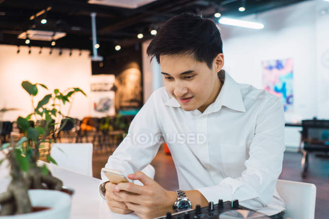 Jeune asiatique homme d'affaires en utilisant smartphone au bureau — Photo de stock