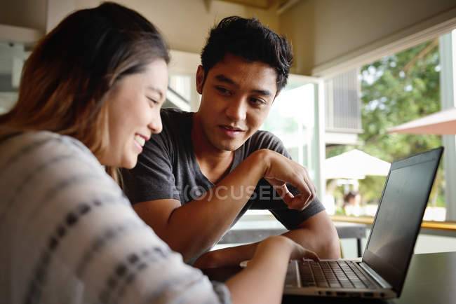 Молода приваблива азіатська пара використовує ноутбук разом — стокове фото