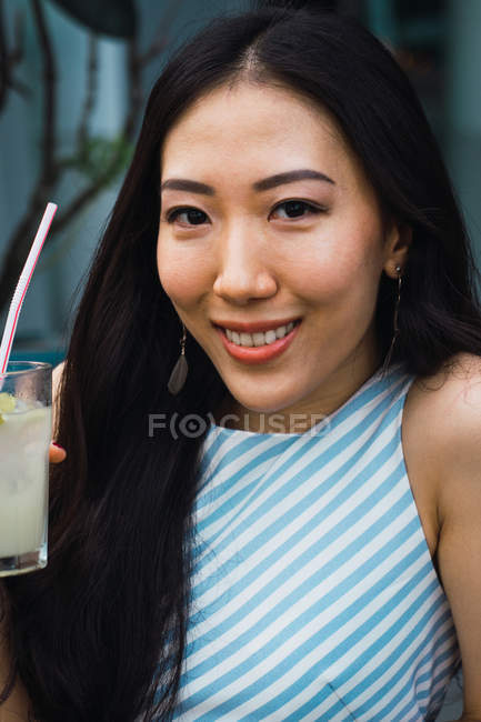Retrato de sonriente joven asiático mujer con bebida - foto de stock