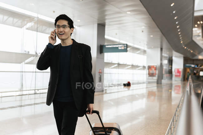 Jovem asiático empresário com bagagem e smartphone no aeroporto — Fotografia de Stock