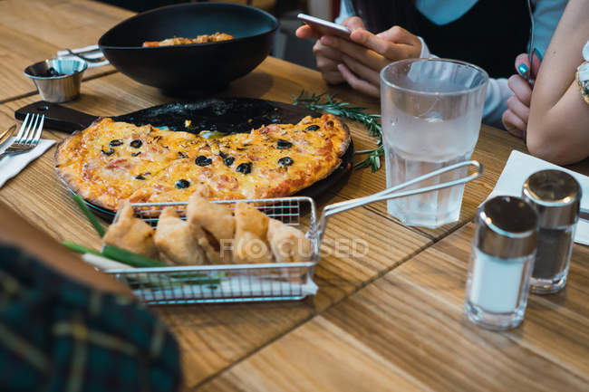Imagem recortada de mãos femininas na mesa com diferentes pratos em bar confortável — Fotografia de Stock