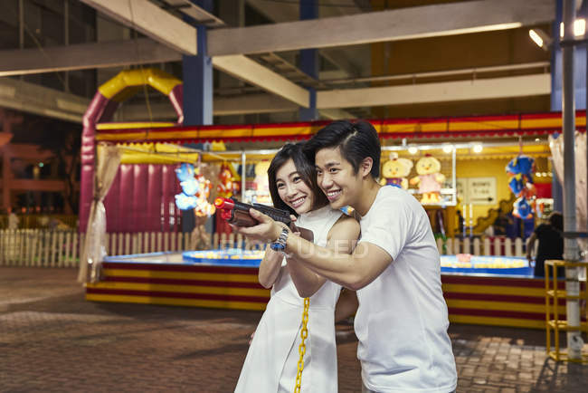 Paar spielt ein Ballerspiel auf einem Karneval, um Preise in Singapore zu gewinnen — Stockfoto