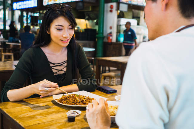 Jovem asiático casal comer comida no café — Fotografia de Stock