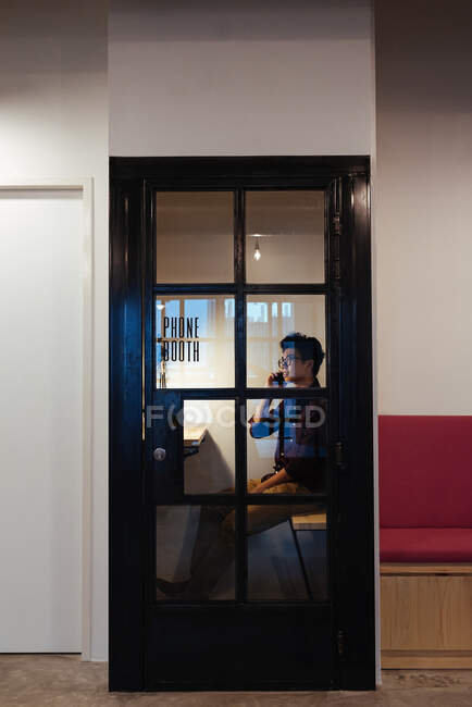 Asiatischer Mann mit Brille auf Handy im Büro — Stockfoto
