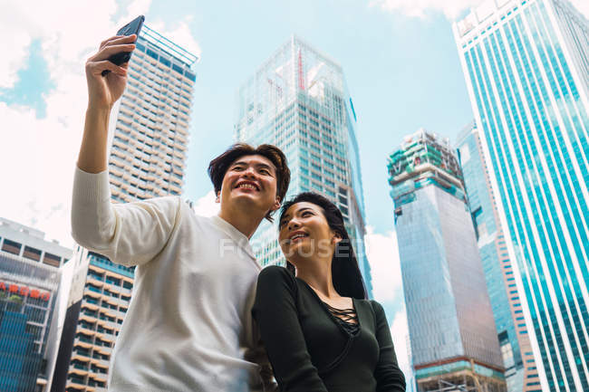 Young asian couple taking selfie on city street — Stock Photo