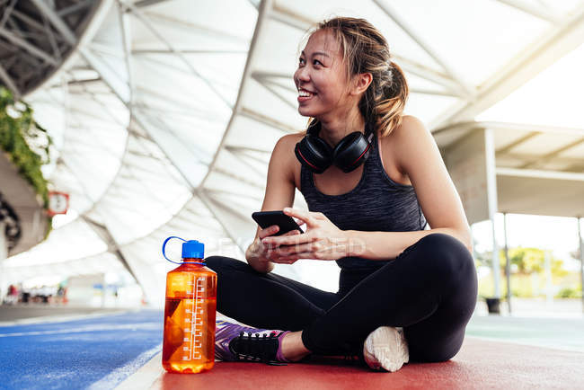 Asian woman in Fitness wear using smartphone while sitting — Stock Photo