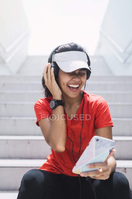 Jovem asiático mulher desportiva usando fones de ouvido e inteligente — Fotografia de Stock