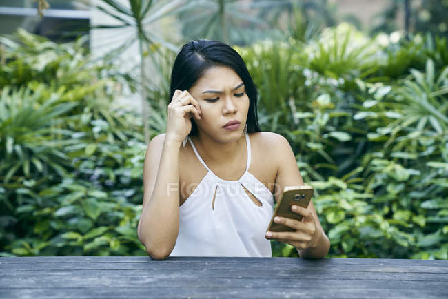 Mujer joven frustrada en su teléfono celular al aire libre - foto de stock