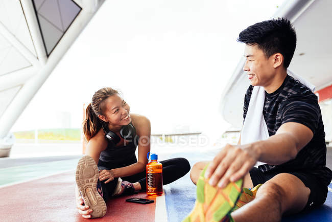 Happy asian sporty couple stretching together — Stock Photo