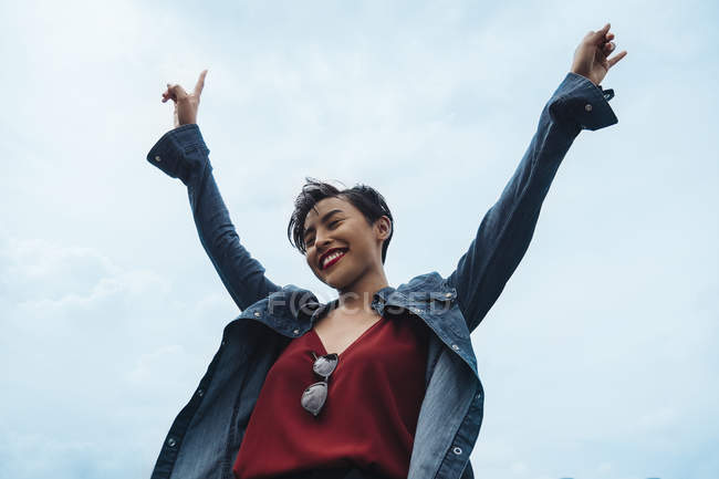 Una feliz y alegre joven malaya en Singapur lanzando sus manos al aire y sonriendo . - foto de stock