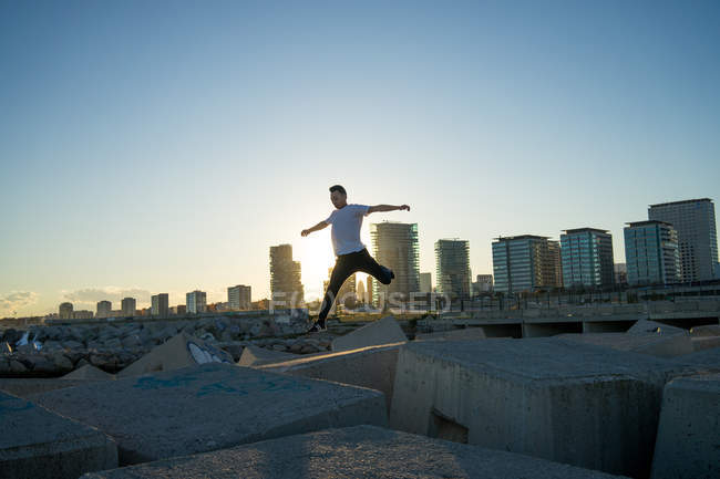 Junger asiatischer Mann springt bei Sonnenuntergang auf Klötze — Stockfoto