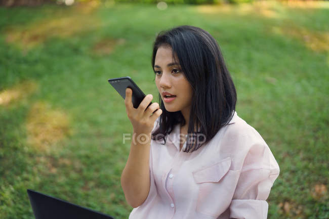 Heureux asiatique femme en utilisant smartphone dans parc — Photo de stock