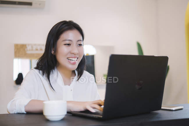 Молодая азиатка работает с ноутбуком в креативном современном офисе — стоковое фото