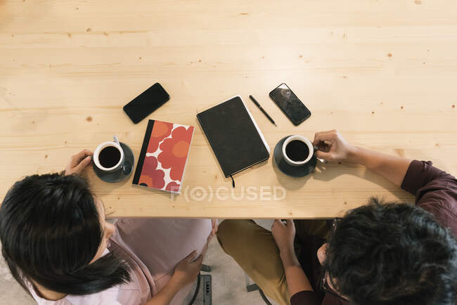 Vista superior de dos trabajadores asiáticos tomando café juntos - foto de stock