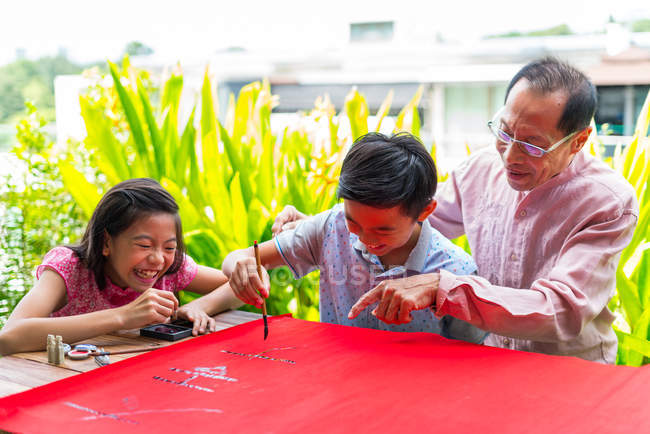 Heureux asiatique famille ensemble, grand-père et petits-enfants dessin hiéroglyphes — Photo de stock