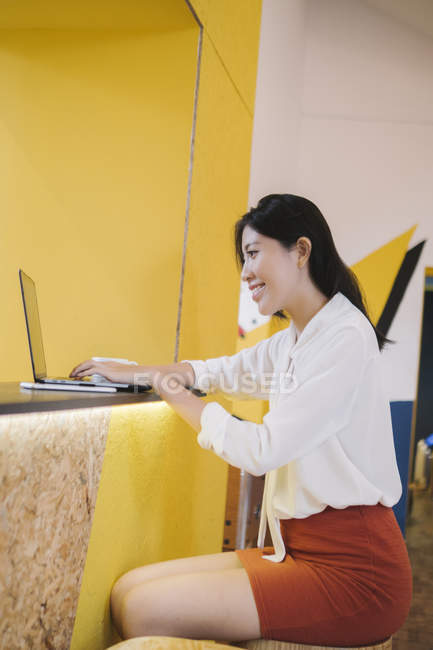 Giovane donna asiatica utilizzando il computer portatile in ufficio creativo moderno — Foto stock