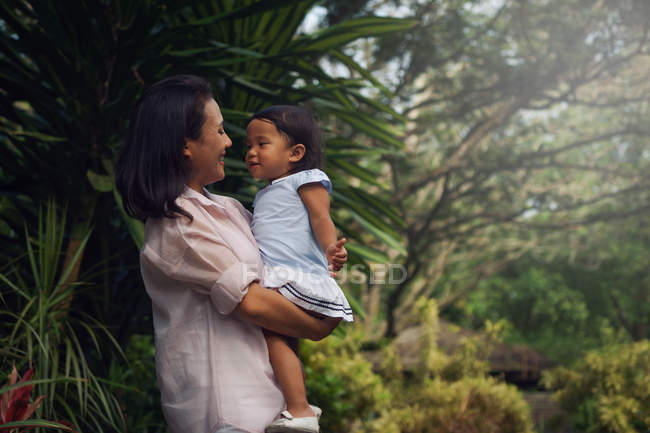 Милая азиатская мать и дочь обнимаются в парке — стоковое фото
