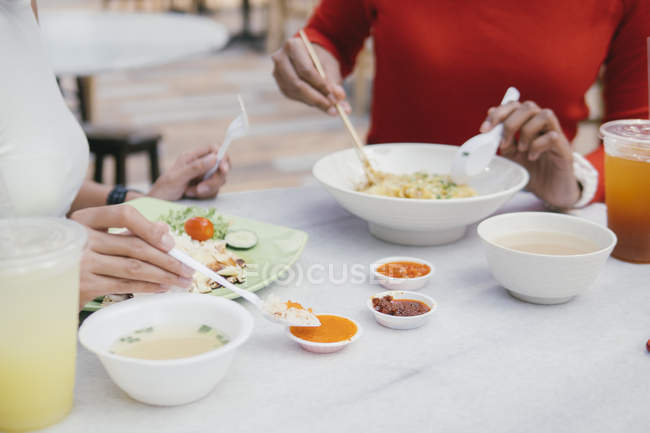 Обрізане зображення друзів-жінок, які їдять їжу на корті — стокове фото