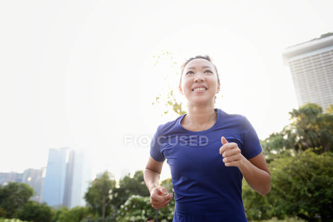 Young asian sporty woman running in city — Stock Photo