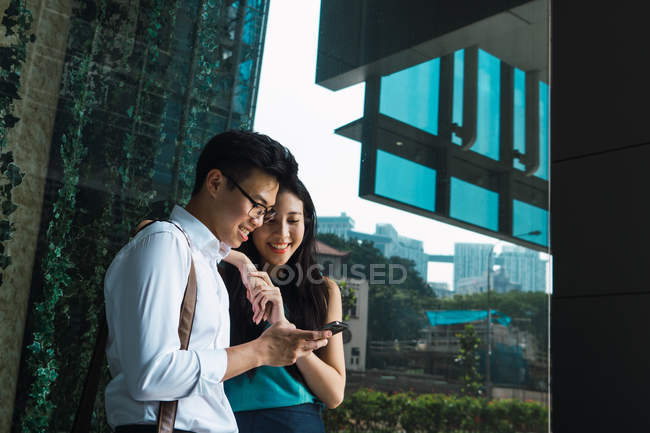 Young adult business couple using smartphone together — Stock Photo