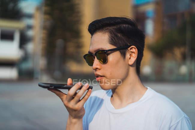 Cool giovane asiatico uomo utilizzando smartphone all'aperto — Foto stock