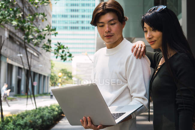 Молодая азиатская пара делится ноутбуком на открытом воздухе — стоковое фото