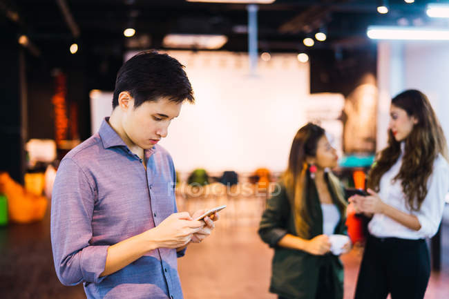 Junger asiatischer Geschäftsmann mit Smartphone im modernen Büro — Stockfoto