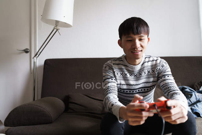 Chinese man at home playing video games — Stock Photo
