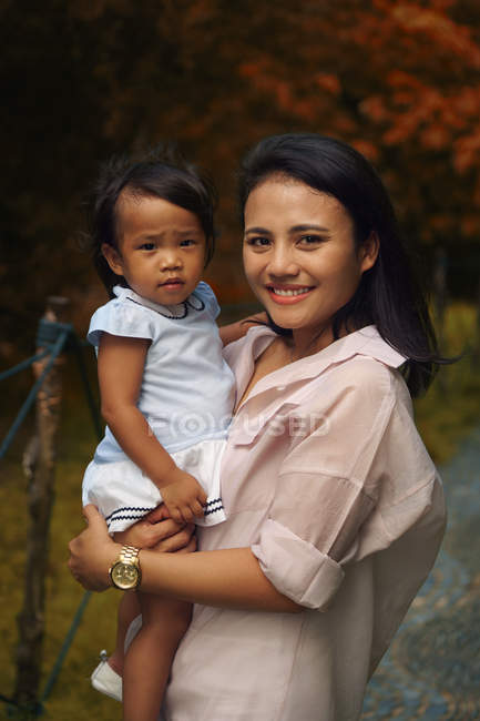 Lindo asiático madre y hija abrazando en parque, retrato - foto de stock