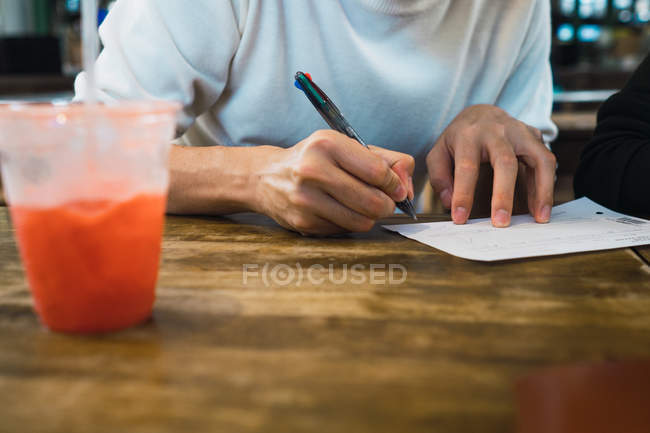 Immagine ritagliata di uomo scrittura nota in caffè — Foto stock