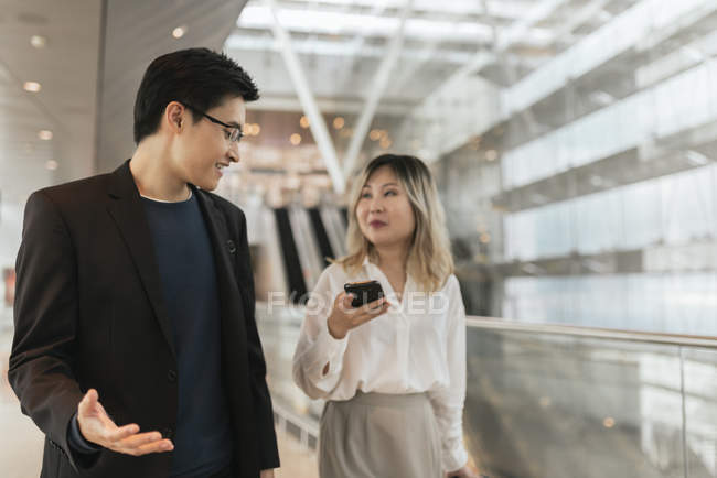 Young asian couple of businesspeople walking in airport — Stock Photo
