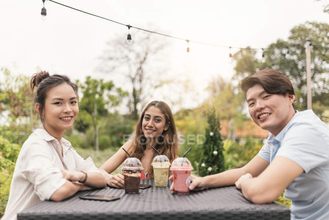 Group of friends at a restaurant, smiling at camera — Stock Photo