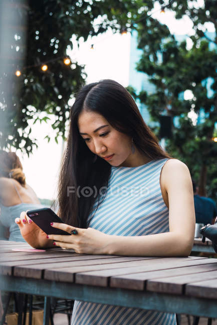 Молода азіатська жінка використовує смартфон на відкритому повітрі — стокове фото