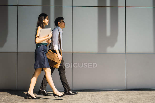 Vista lateral de jovens adultos casal de negócios caminhando — Fotografia de Stock