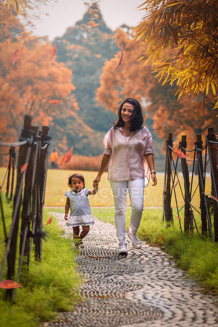 Милая азиатская мать и дочь, идущие по дорожке в парке — стоковое фото