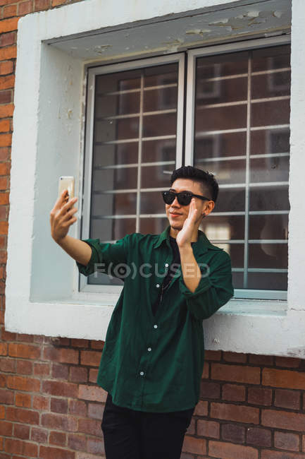 Крутой молодой человек с помощью смартфона на улице — стоковое фото