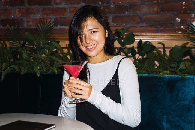 Junge asiatische Frau mit Cocktail in bequemer Bar — Stockfoto