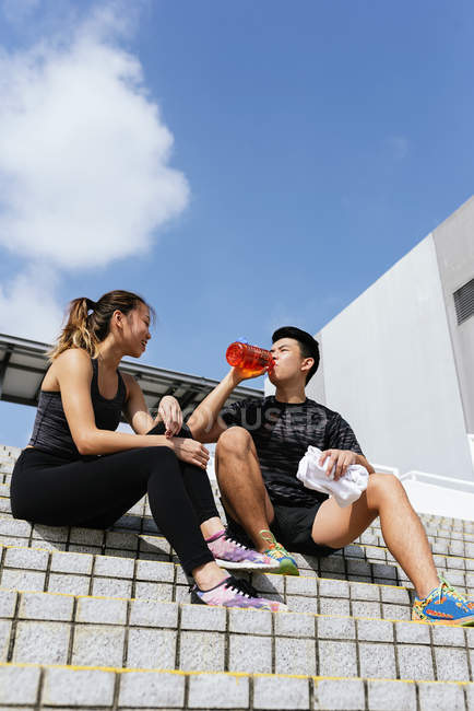 Heureux asiatique sportif couple potable eau sur stade — Photo de stock