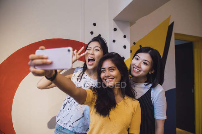 Молоді азіатські жінки беруть селфі в творчому сучасному офісі — стокове фото