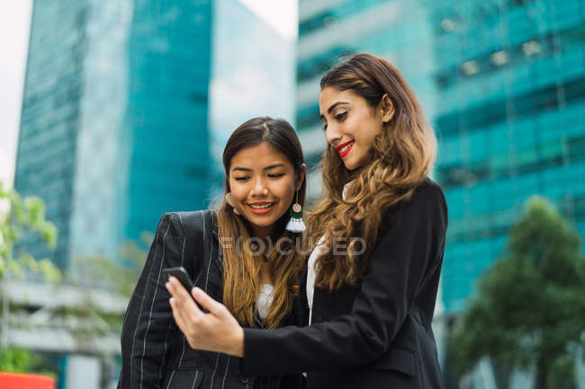 Jeunes femmes d'affaires asiatiques utilisant un smartphone — Photo de stock