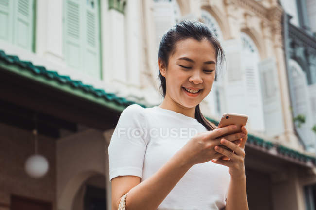 Young attractive asian woman using smartphone outdoors — Stock Photo