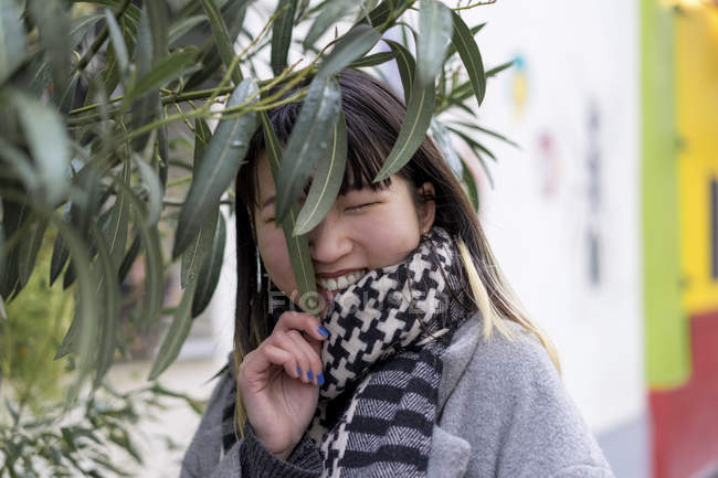 Jovem atraente casual asiático sorrindo perto de planta — Fotografia de Stock